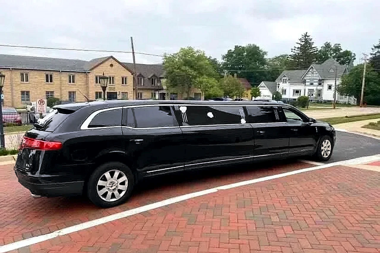 Black Lincoln MKT stretch limousine with white wedding ribbons on a brick street